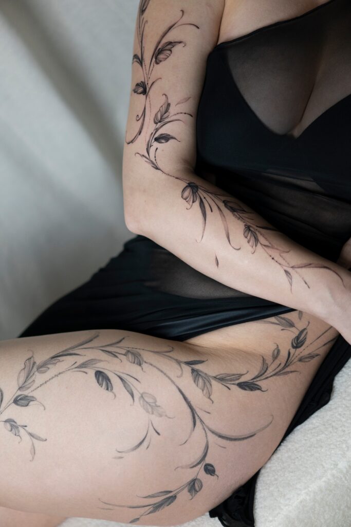 Botaniczny tatuaż fineline oplatający ramię i biodro wykonany w Częstochowie.